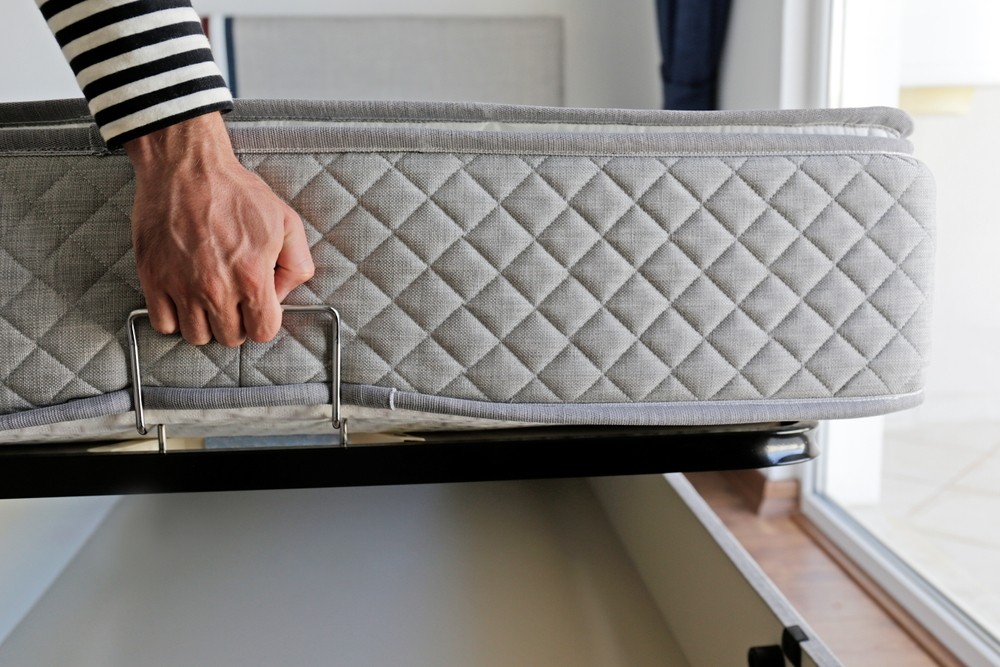 picture of person carefully moving a bed mattress